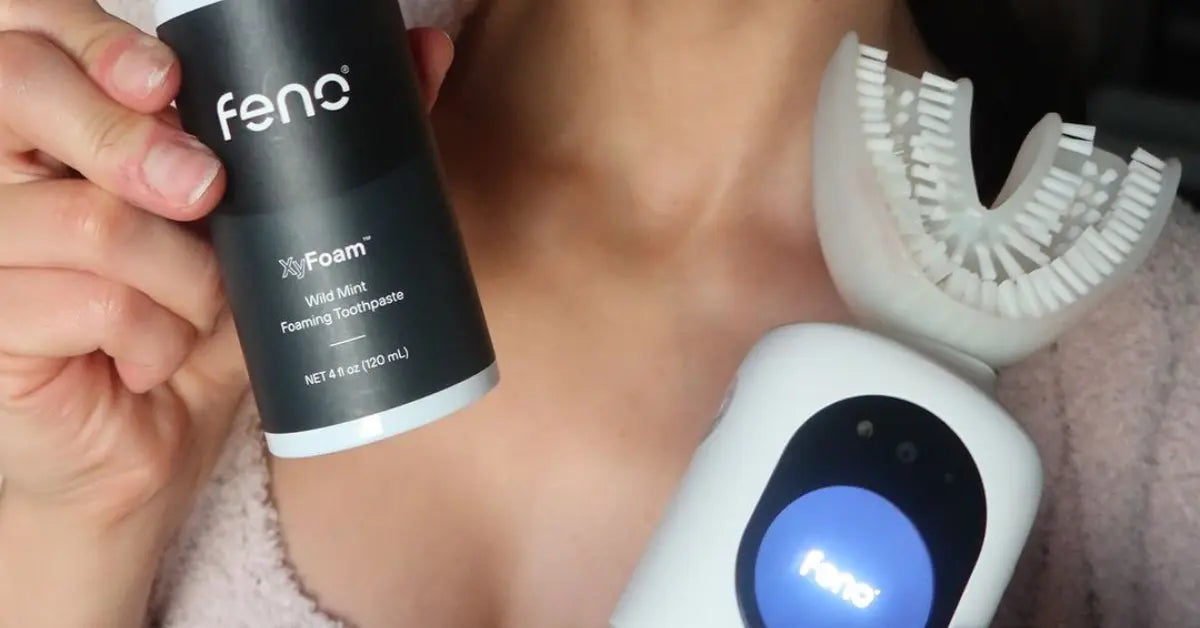 Feno smart toothbrush and XyFoam toothpaste held by a person, showcasing dental care products