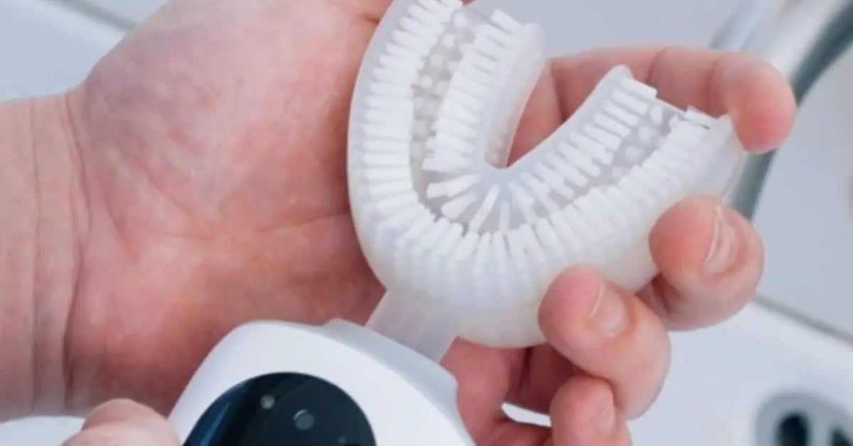 Close-up of a person holding the detachable U-shaped brush head of the Feno automatic toothbrush