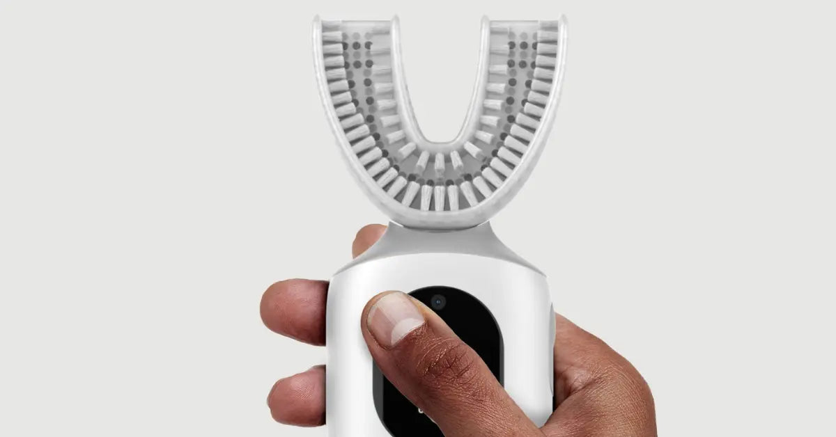 Hand holding the Feno automatic toothbrush, highlighting its U-shaped brush design and compact build