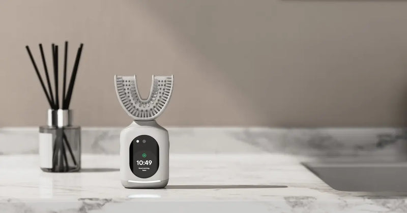 Smart toothbrush with U-shaped design and digital display on a marble bathroom counter.