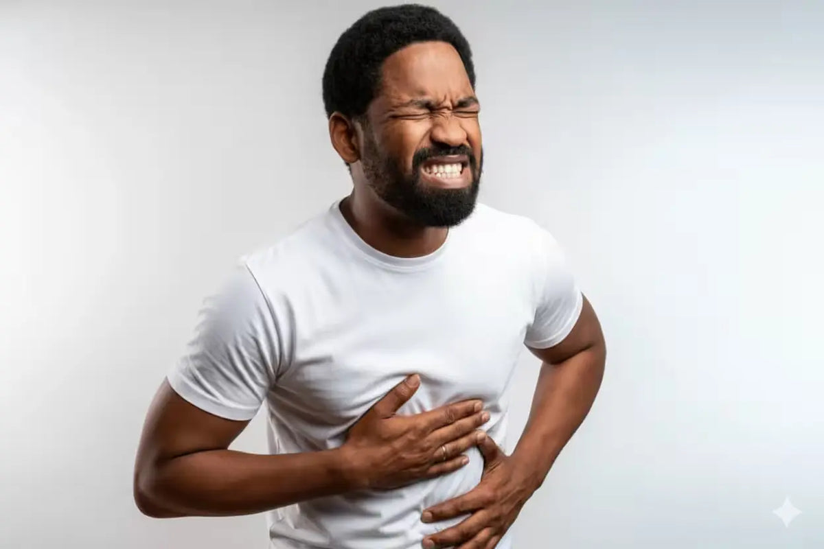Person in white shirt clutching chest and stomach, grimacing from acid reflux discomfort.