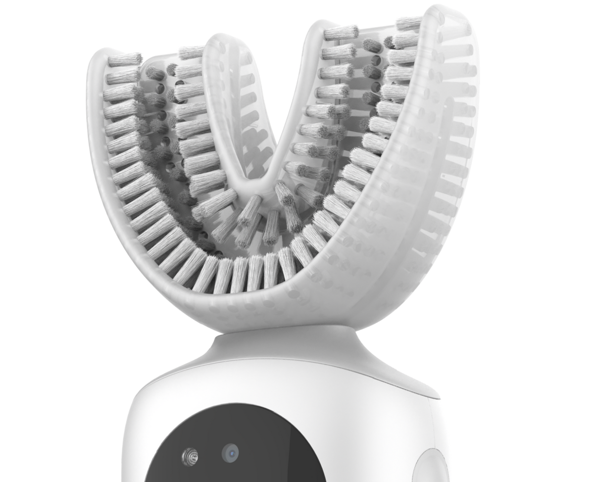Close-up of a U-shaped toothbrush mouthpiece with white bristles on Feno's device.