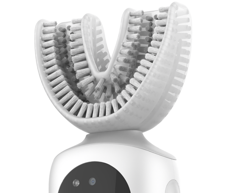 Close-up of a U-shaped toothbrush mouthpiece with white bristles on Feno's device.