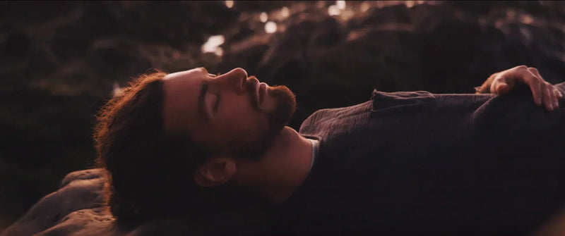 Bearded person resting with eyes closed in warm light, illustrating oral health and sleep.