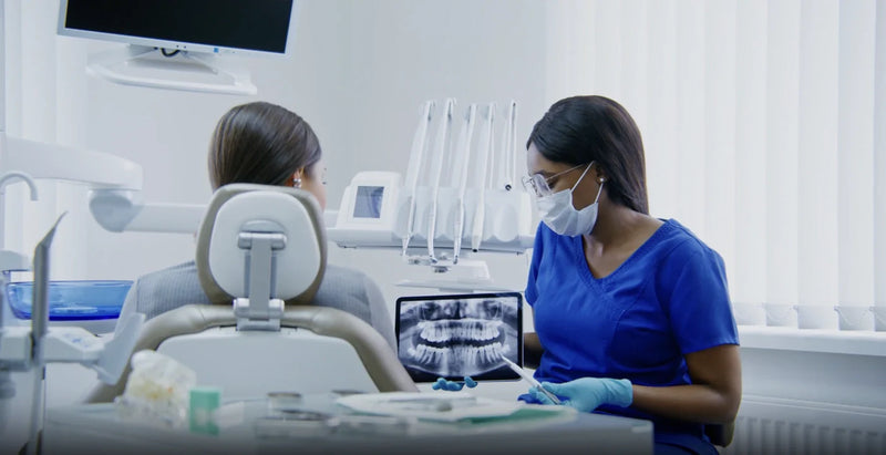 Dental professional reviewing a jaw X-ray on a tablet during an oral cancer screening.
