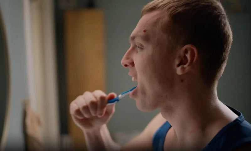 Person brushing teeth with a manual toothbrush, illustrating daily autism dental care routines.