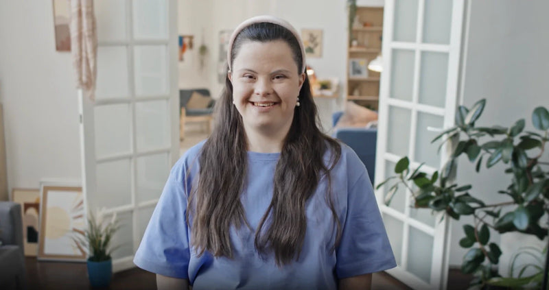 Smiling person with Down syndrome standing at home, illustrating Down syndrome oral health care.
