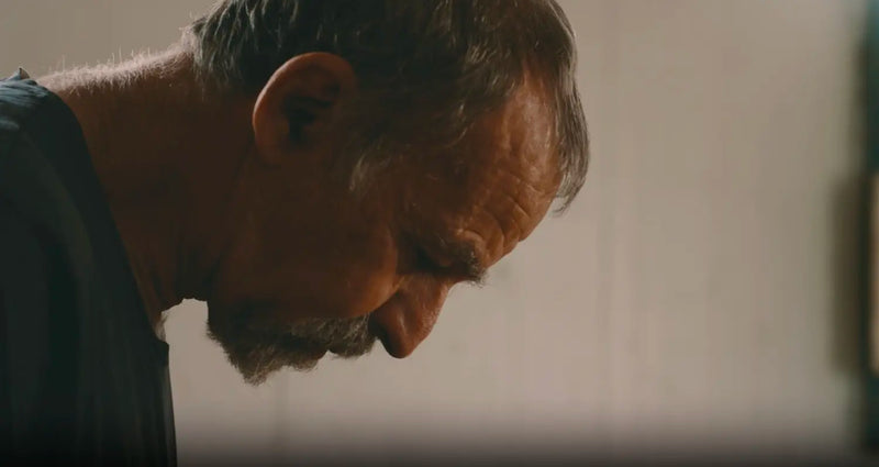 Profile of a bearded person with head bowed, illustrating the weight of trauma and PTSD.