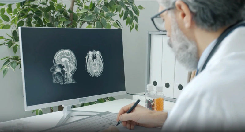 Physician studying brain MRI scans on a monitor, illustrating oral bacteria brain infection risks.