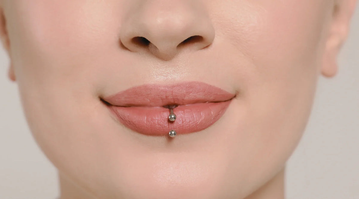 Close-up of a lower lip piercing with a metal barbell studs.