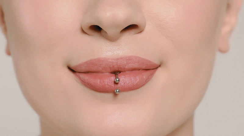Close-up of a lower lip piercing with a metal barbell studs.