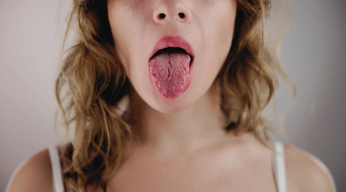 Person sticking out tongue to reveal a coated surface signaling immune health clues.