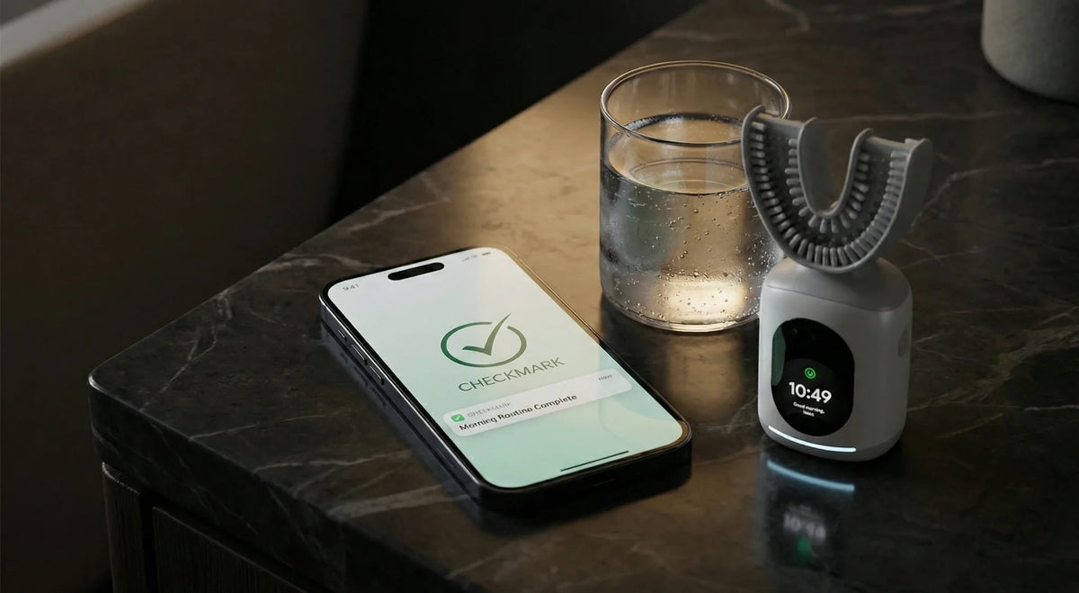 U-shaped smart toothbrush on charging base beside phone showing a completed morning routine reminder.
