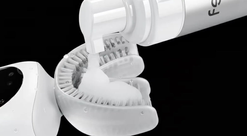 Toothpaste applied to a U-shaped toothbrush mouthpiece with nylon bristles on black.