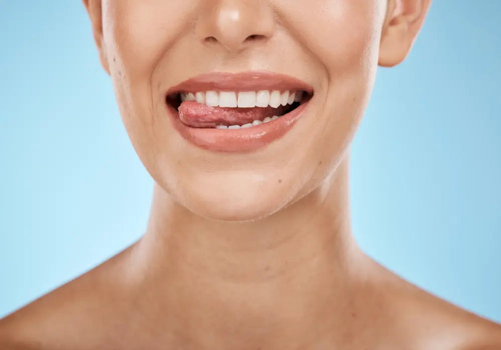 A woman with a bright smile licking her teeth, illustrating the benefits of a U-shaped toothbrush for oral hygiene.