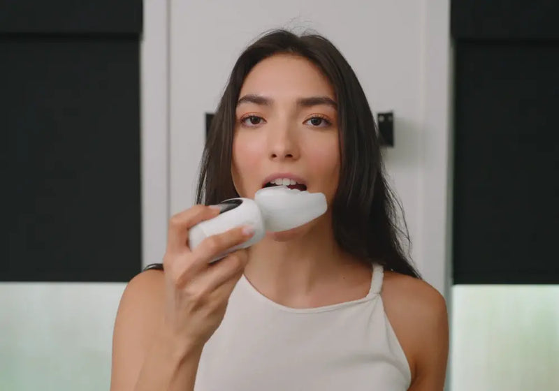 A woman uses a high-tech smart toothbrush with a mouthpiece design for efficient dental care.