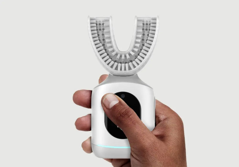 U-shaped toothbrush held in a hand, featuring a modern automatic design with silicone bristles and ergonomic handle.