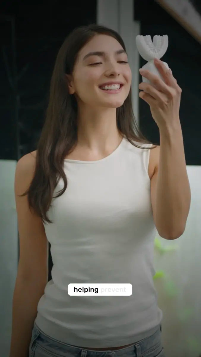 Smiling person holding a white U-shaped toothbrush up beside their face in a bathroom.