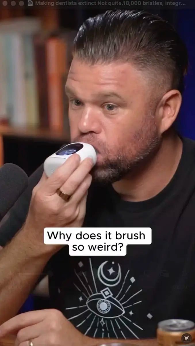Person holding a U-shaped smart toothbrush in their mouth during a podcast, captioned why it brushes so weird.