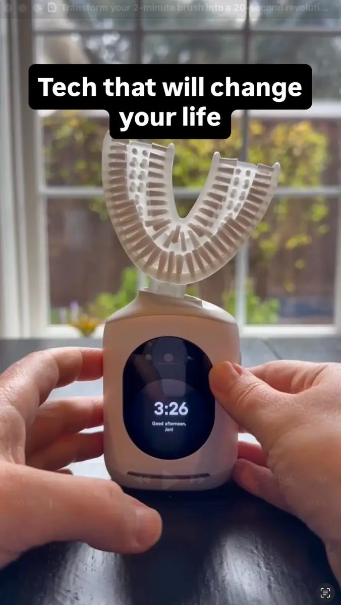 Hands holding Feno U-shaped smart toothbrush with digital display base near a sunny window.